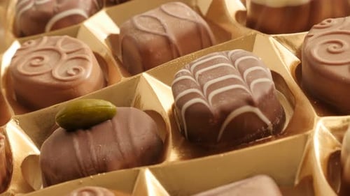 Golden package box of chocolates many different candies slow tilt 4K 2160p 30fps UltraHD footage - T
