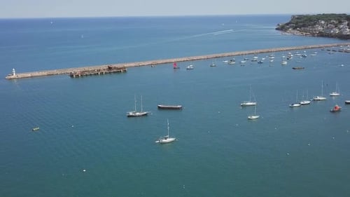 Aerial dolly out of a beautiful quay and Marina, with sail boats moored.