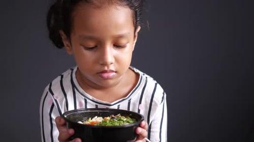 Child Holding a Bowl of Green Vegetables