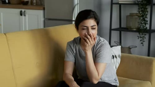 Müde junge Frau gähnt und legt sich hin, um sich zu Hause im Zimmer auf dem Sofa auszuruhen
