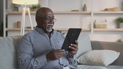 Senior Man Using Tablet Device on Couch