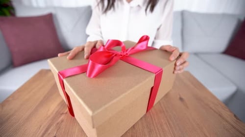 Woman Tying Pink Ribbon on Birthday Gift