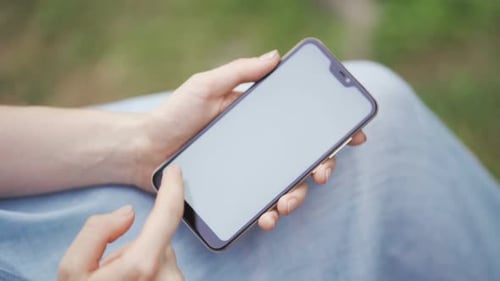 A Girl Uses Her Smartphone in the Park Browses Social Networks Watches News