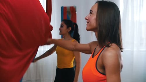 Women Prepare for Aerial Yoga in Bright Studio