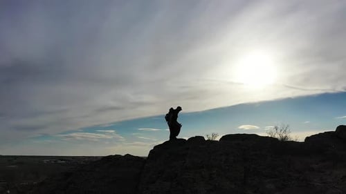 Silhouette of a Man Walking Along a Ridge