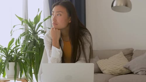Woman with Laptop Ponders in Bright Home