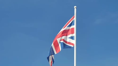 British Union Jack Flag Waving Against Blue Sky