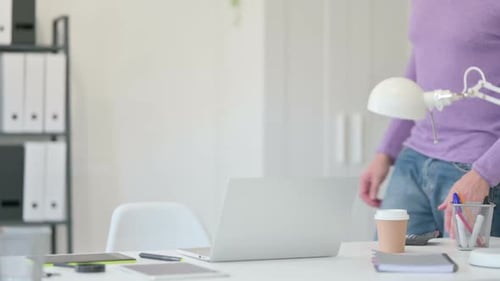 Man Sits Down at Desk and Types on Laptop