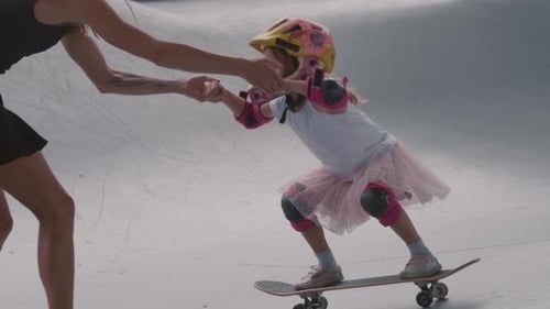 Child Learning Skateboarding with Adult Assistance
