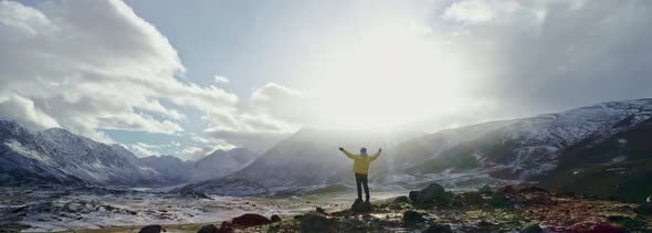 A Man Stands on Top of a Cliff and Enjoys a Beautiful View