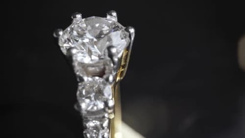 Extrem detaillierte Nahaufnahme des Diamantrings beim Drehen auf dunklem Hintergrund