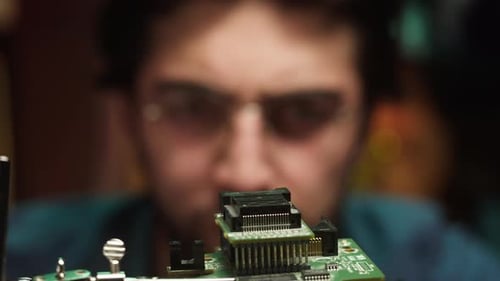 Focused Young Adult Repairs Computer Circuit Board