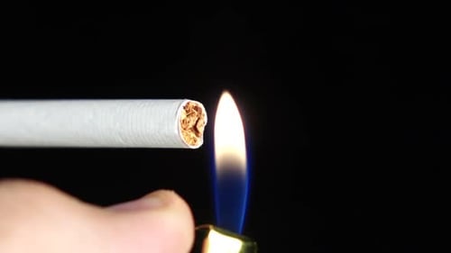 Hombre a punto de encender un cigarrillo con encendedor. negro. De cerca. Cámara lenta