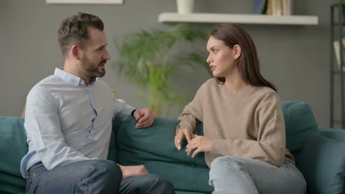 Pareja teniendo una conversación seria mientras está sentado en el sofá