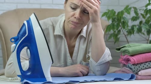 Tired Woman Ironing Clothes at Home