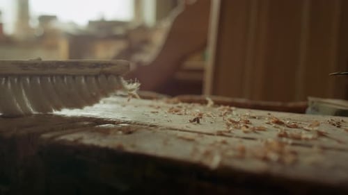 Woodworker Sweeping Wood Shavings off Workbench with Brush