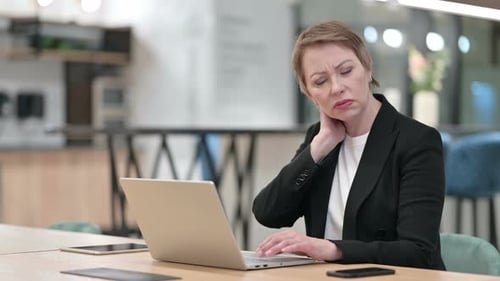 Tired Old Businesswoman Having Neck Pain in Office