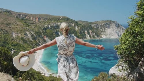 Woman Traveller on Top of Mountain Raising Her Hands Enjoying Beautiful Blue Sea Lagoon Celebrating