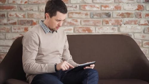 Man Using Tablet Computer on Couch at Home