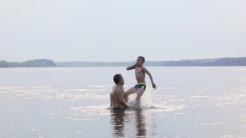 Father and Son Playfully Swimming in Calm Lake