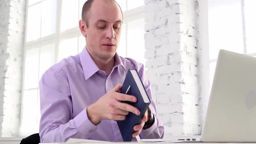 Man Working on Laptop and Reading Book