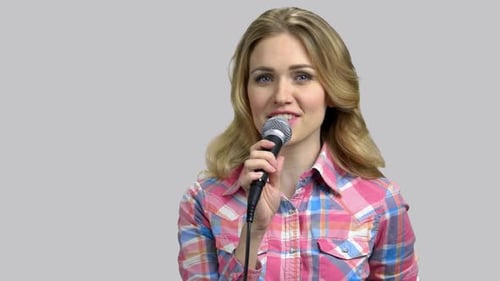 Woman Talking into Microphone on Gray Background