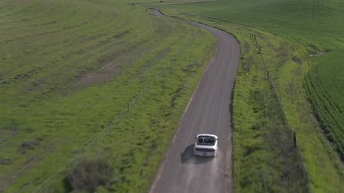 Car Driving On The Dirt Road Among Windmills
