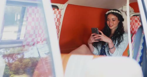 Young Woman Using Phone inside Camper Van
