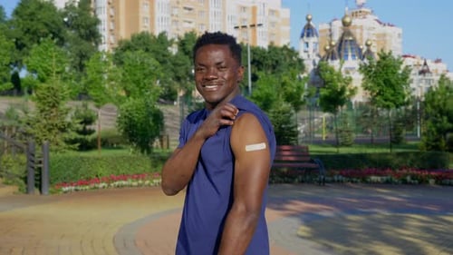 Smiling Man Shows Arm Bandage After Vaccination
