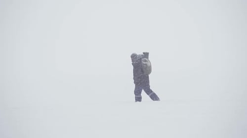 Person Walking Through Blizzard in Snowy Wilderness