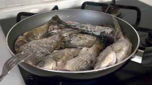 Sea fish is fried in a frying pan for lunch with close up view.