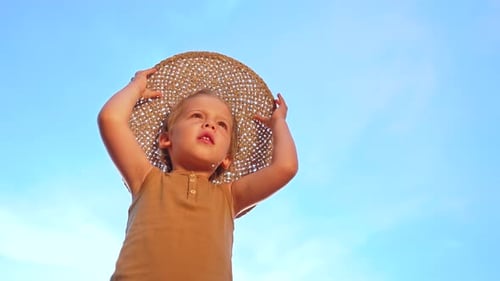 Child in Straw Hat Posing Outdoors