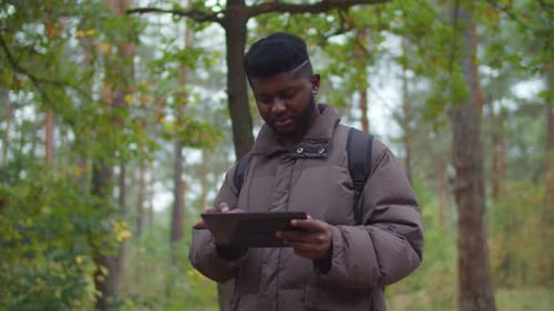Hombre excursionista africano usando la aplicación GPS en una tableta digital