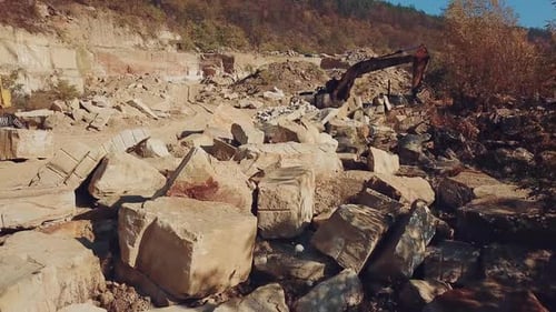professional equipment are working in the quarry with stones on the background of a hill