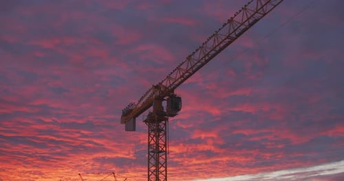 Construction Cranes at Colorful Sunrise or Sunset