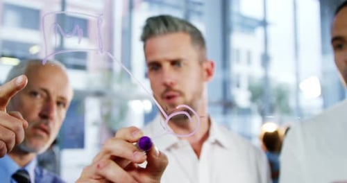 Business colleagues talking while writing on glass window