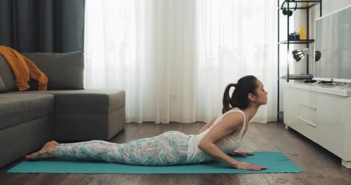 Woman Doing Cobra Pose in a Bright Living Room