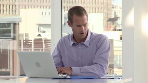 Businessman Using Laptop and Making Notes in Office