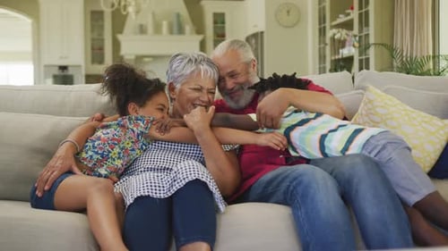 Grandparents Receiving Affectionate Hugs From Grandchildren on Couch