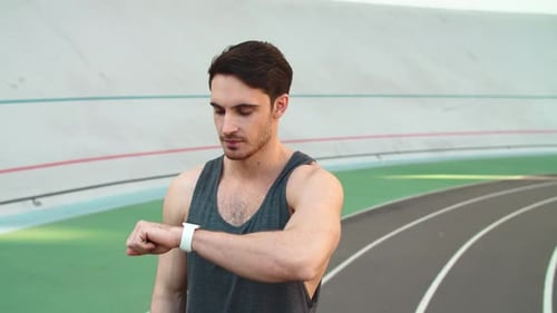 Man Checking Smartwatch on Running Track
