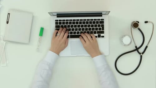Doctor Typing on Laptop in Bright Office