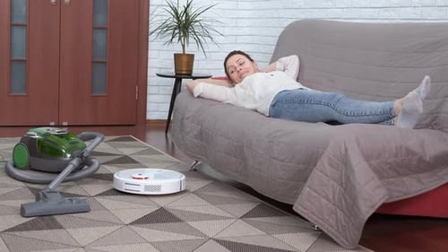 Woman Lying Down as Robot Vacuum Cleans