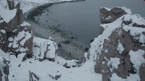 Top View of the Coast of the Sea Surrounded By Snowy Rocks and a Man at the Foot Makes His Way