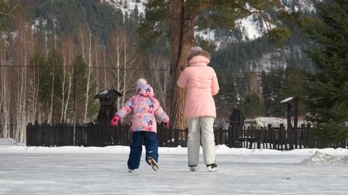 Woman with Daughter Skating on Winter Ice Rink