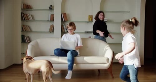 Müde Frau sitzt genervt auf der Couch, während eine laute kleine Tochter schreit springt auf die Couch