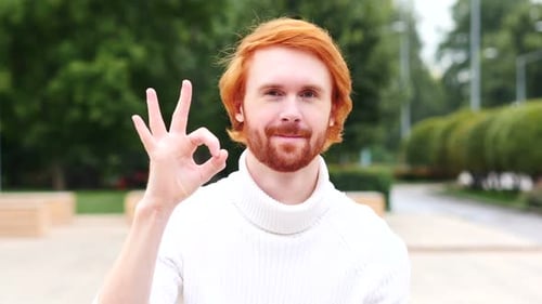 Red Haired Man Gives OK Hand Gesture in Park