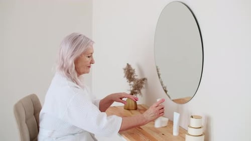 Senior Woman Applying Hand Cream in Bright Bathroom