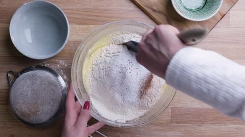 Weibliche Hände mischen Zutaten zu Karottenkuchenteig.
