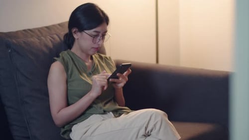 Woman Using Smartphone on Couch Indoors