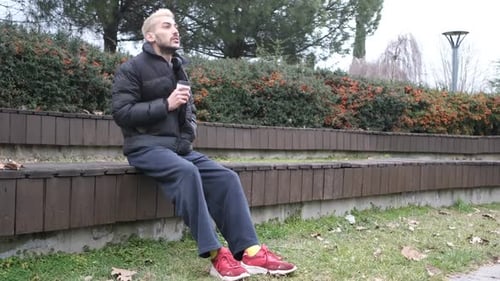 Man Drinking Coffee Alone on Park Bench